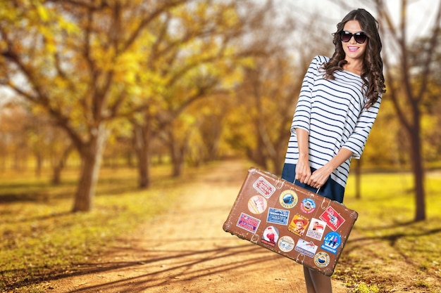 Beautiful blonde girl with her luggage on a beach