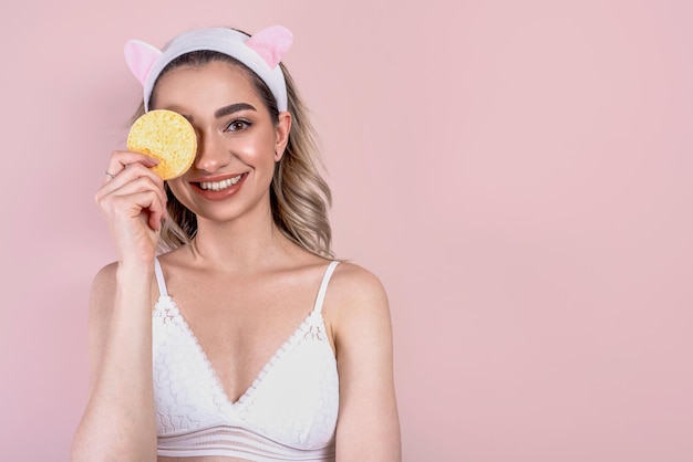 Beautiful blonde girl with a sponge in her hand face care morning routine cleaning