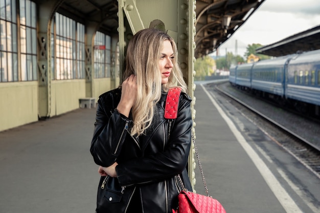 Beautiful blonde in a leather jacket at the train station