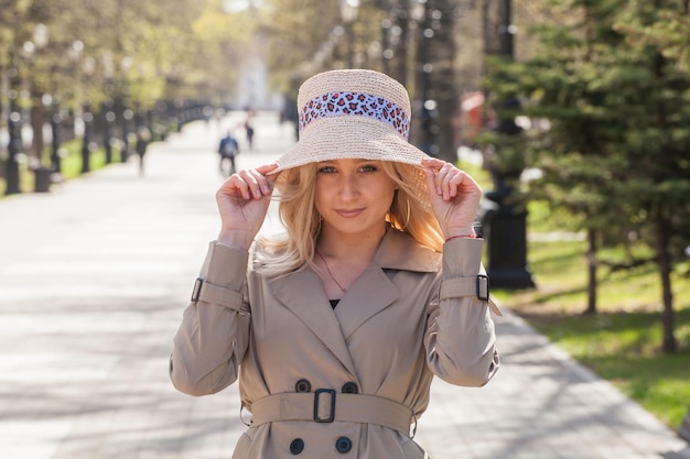 Beautiful blonde in a raincoat and hat on a walk in the park