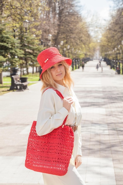 Beautiful blonde on a walk with a bag and a handmade red hat