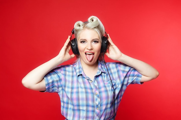 Beautiful blonde with headphones posing on a red background