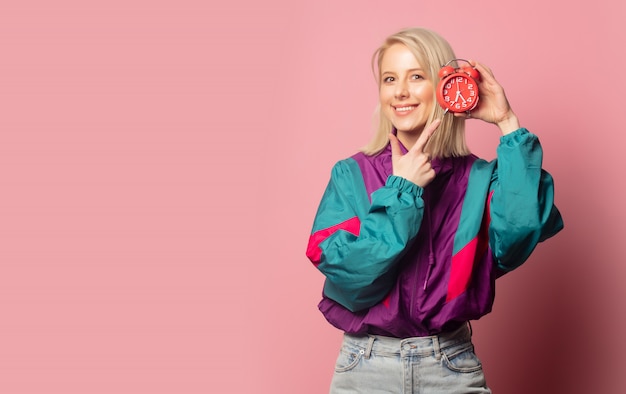 Beautiful blonde woman in 90s clothes with alarm clock