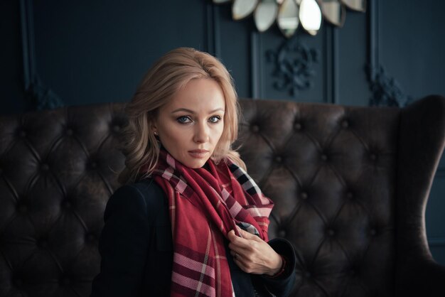 Beautiful blonde woman in a blue autumn coat and a red scarf. Bare legs in contrast.