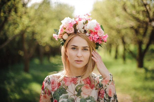 Beautiful blonde woman dressed in flower dress and pink wreath