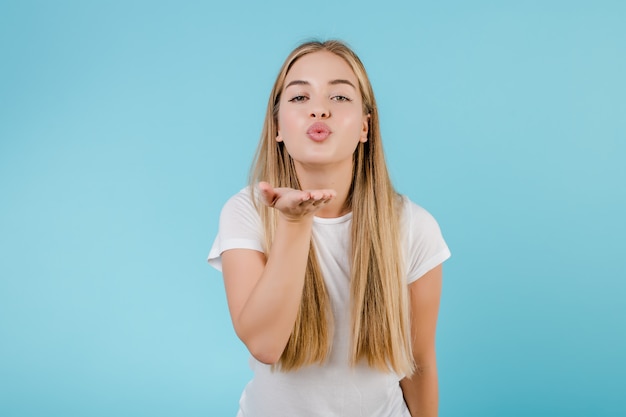 Beautiful blonde woman sending smooch kiss isolated over blue