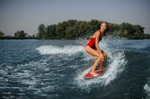 Photo beautiful blonde woman surfer riding down the blue splashing wave