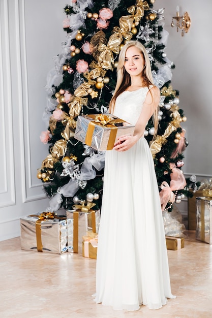 Beautiful blonde woman in a white dress with a gift