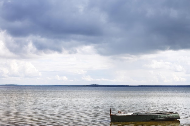 Beautiful blue lake landscape with a boat and clouds in the sky