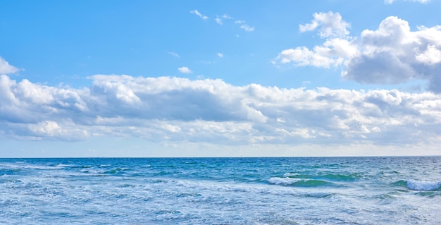 Beautiful blue ocean view of the sea with white clouds on a beach day in summer Outdoors tidal landscape of calm water sky and waves in nature Peaceful outdoor coastal setting outside