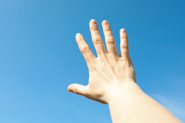 Beautiful blue sky background with woman hand. Wonderful skies