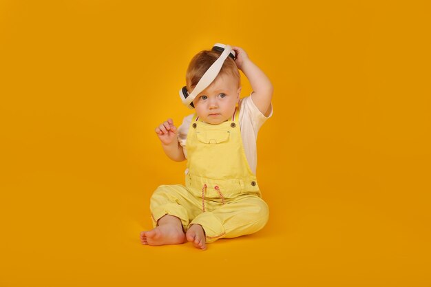 a beautiful blueeyed little boy in a yellow suit is sitting in white headphones