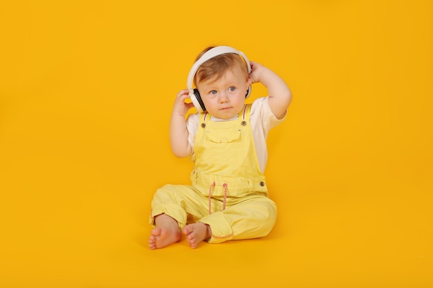 a beautiful blueeyed little boy in a yellow suit is sitting in white headphones