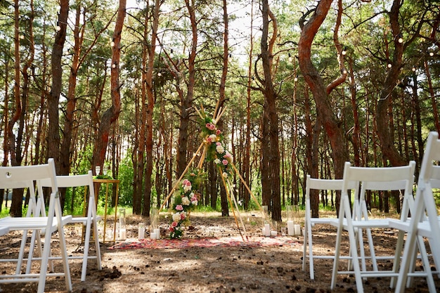 Beautiful bohemian tipi arch decoration on outdoor wedding ceremony venue in pine forest with cones