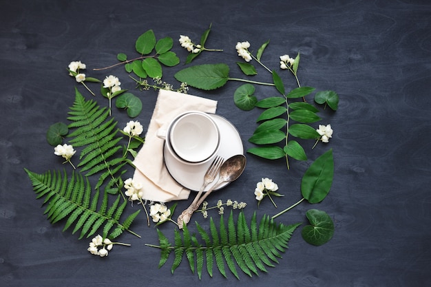 Beautiful boho spring table set up mockup with wild flower and plant decoration. Trendy flat lay top view photo.