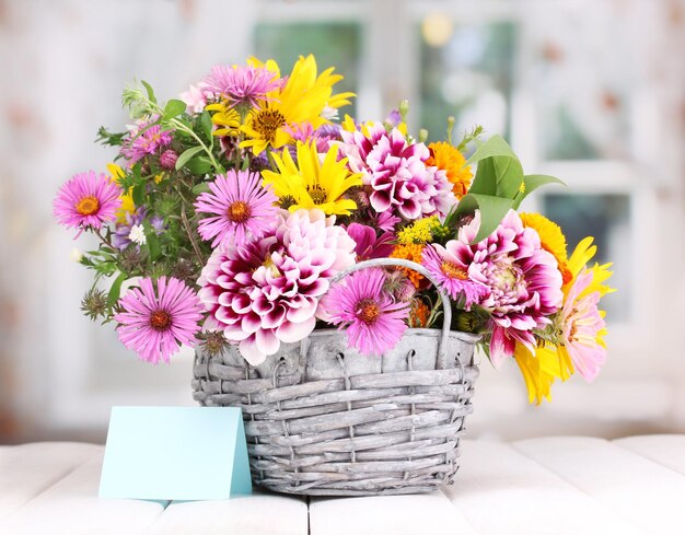 Beautiful bouquet of bright flowers in basket on wooden table