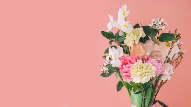 Beautiful bouquet of carnations daffodils Chamelacium hookata and white irises on peach background