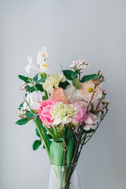 Beautiful bouquet of carnations daffodils spray roses Chamelacium hookata and white irises on gray