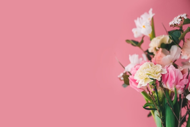 Beautiful bouquet of carnations peony tulips roses and daffodils on a pink background copy space