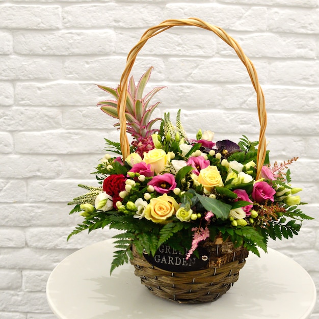 Beautiful bouquet of colorful flowers in  basket on table