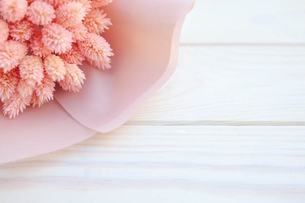 Beautiful bouquet of dry pink flowers on a wooden white background. 