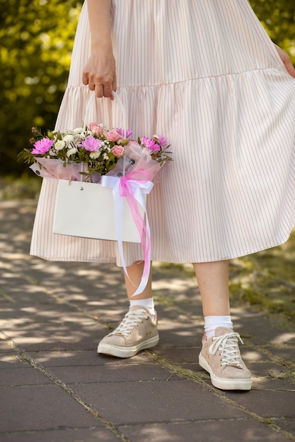 A beautiful bouquet of flowers in a box in the hands of a beautiful girl who walks along the street