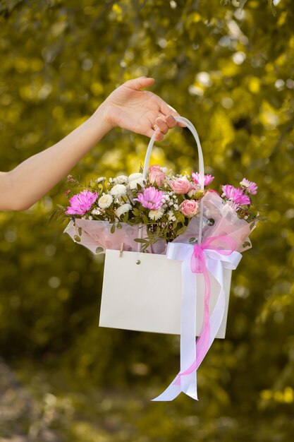 A beautiful bouquet of flowers in a box in the hands of a beautiful girl who walks along the street