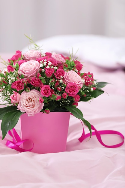 Beautiful bouquet of flowers in paper gift box on bed