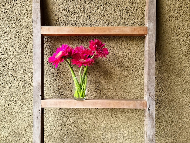 Beautiful bouquet of magenta gerbera flower in the vase put on bathroom wooden ladder