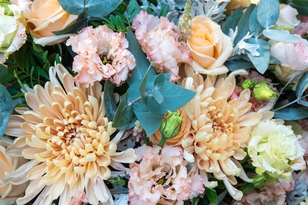 Beautiful bouquet of mixed flowers in a vase on wooden table. the work of the florist at a flower shop. a bright mix of sunflowers, chrysanthemums and roses.