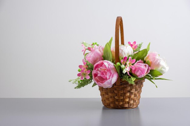 Beautiful bouquet of pink peonies floral composition in straw basket on light gray background