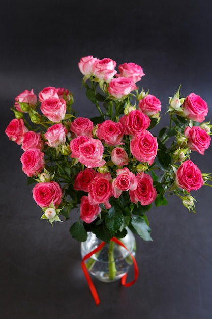 Beautiful bouquet of pink red roses bushes with water drops on a black background Selective focus closeup