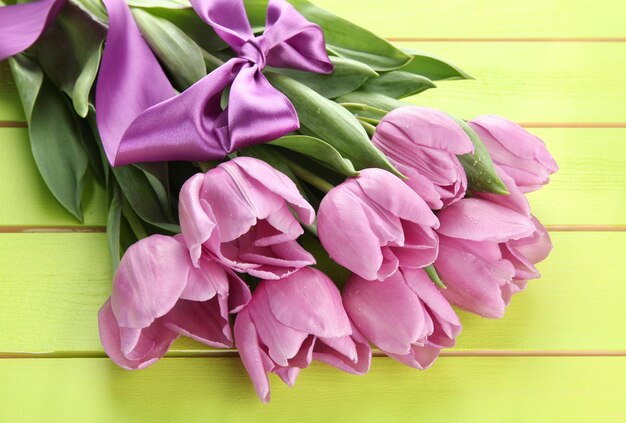 Beautiful bouquet of purple tulips on green wooden background