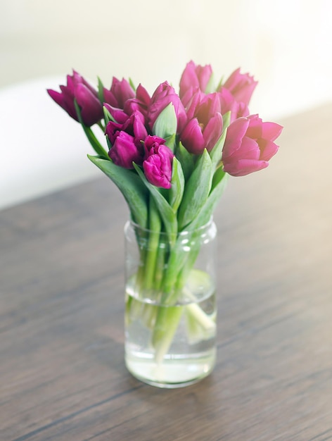 Beautiful bouquet of purple tulips on wooden table at living room