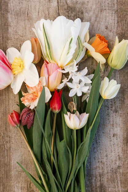 Beautiful bouquet rustic flat lay on aged wooden background Spring daffodils and tulips top view floral rural template Growing spring flowers Mothers day card