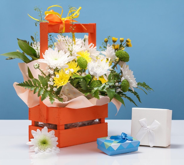 Beautiful bouquet of various flowers and gift boxes on the blue background.