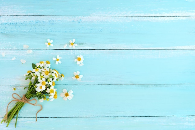 Beautiful bouquet of white wildflowers on blue wooden background