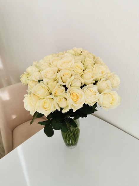 Beautiful bouquets of white roses in a glass vase on a white table and interior 51 roses