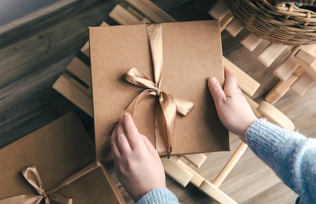 Beautiful box with a bow in female hands top view