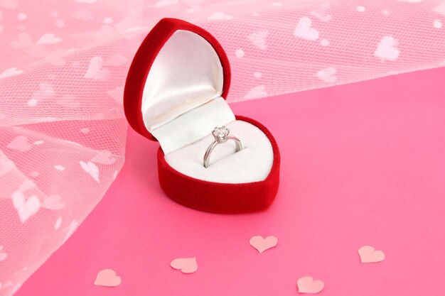 Beautiful box with wedding ring on pink background