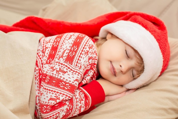 a beautiful boy in New Year's pajamas and a Santa hat is lying in bed