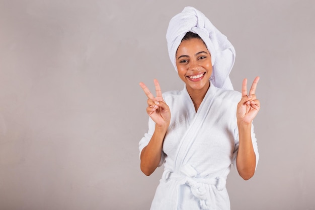 Beautiful Brazilian black woman wearing bathrobe and towel peace and love good vibes smiling