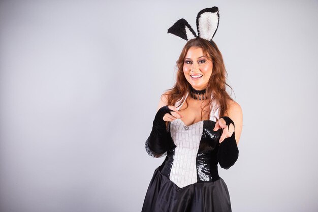 Photo beautiful brazilian woman with rabbit clothes easter pointing at camera choosing you