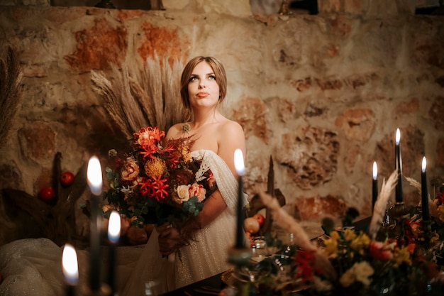 Beautiful bride by wedding table richly decorated in rustic style