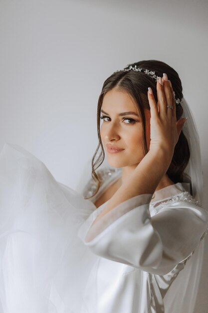 Beautiful bride in a dressing gown in the morning before the wedding ceremony Incredible hairstyle of the bride Natural and modern makeup Portrait of a young bride in a dressing gown