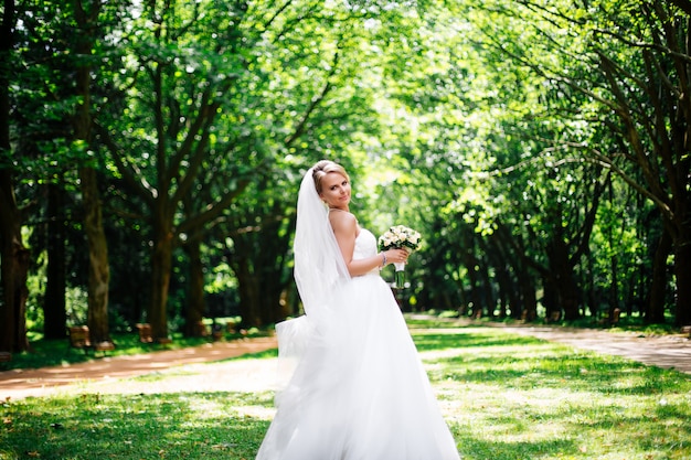 Beautiful bride in fashion wedding dress on natural background.The stunning young bride is incredibly happy. Wedding day.A beautiful bride portrait in the forest.