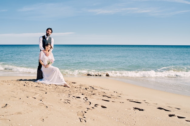 Beautiful bride and groom on the beach looking at each other with much love and joy