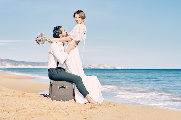 Beautiful bride and groom on the beach looking at each other with much love and joy