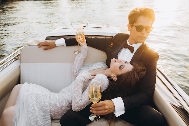 Beautiful bride and groom ride a yacht drink wine and enjoy the moment Wedding day