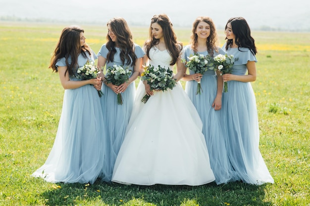 beautiful bride and her bride maids standing with flowers at the nature